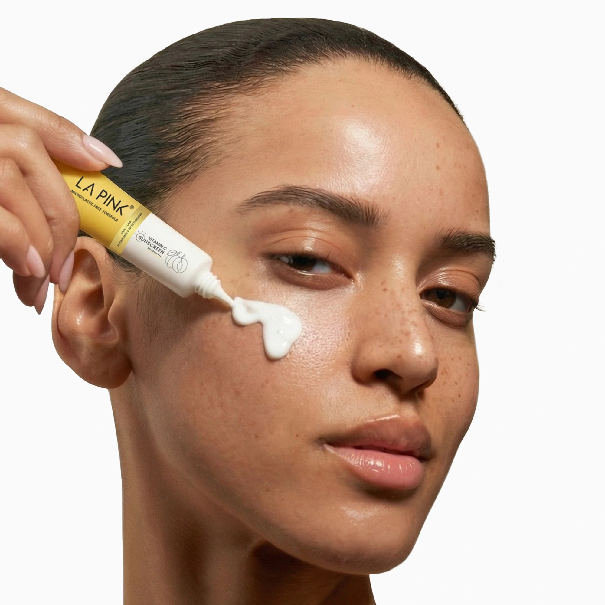 Woman applying cream to her face with a LA Pink tube