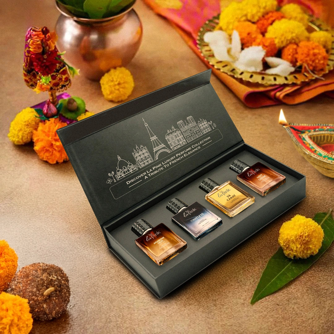 Set of miniature perfume bottles in a decorative box with floral and decorative items on a table.