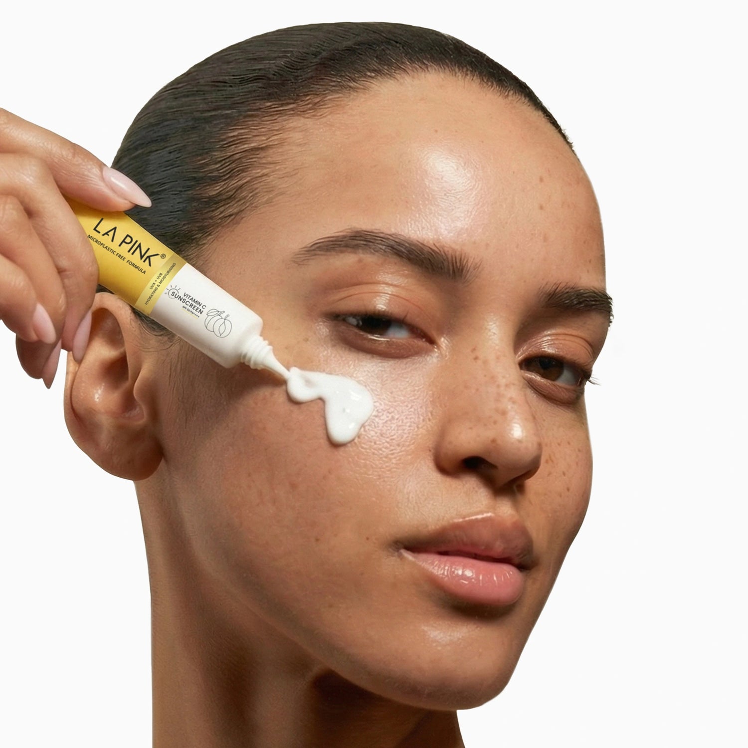 Woman applying cream to her face with a LA Pink tube