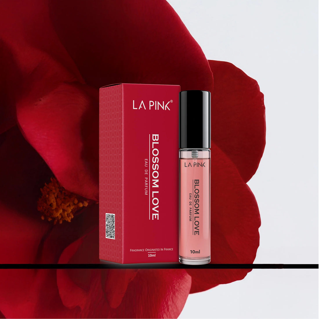 LA Pink Blossom Love perfume bottle and packaging on a red floral background