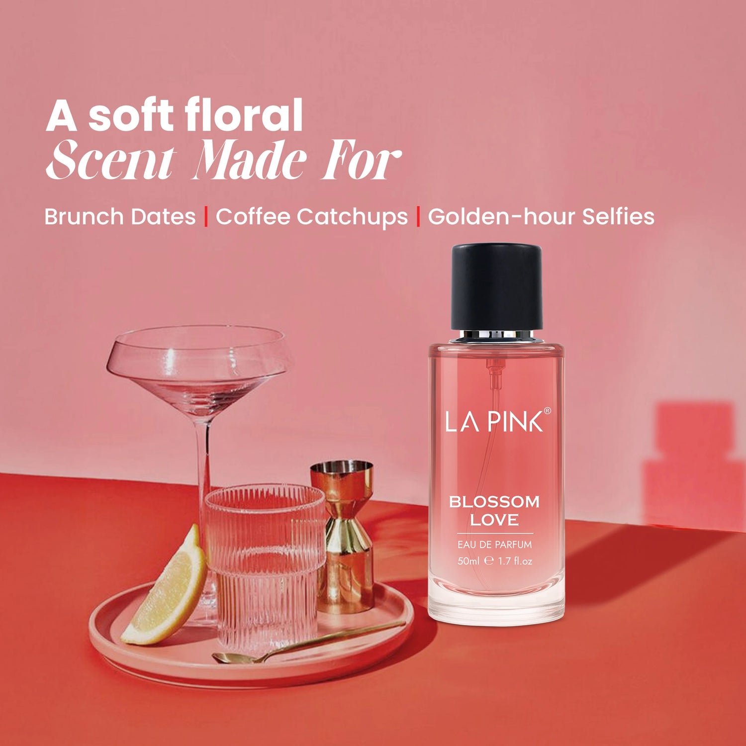 LA Pink Blossom Love perfume bottle on a pink and red background with a glass and lemon wedge.