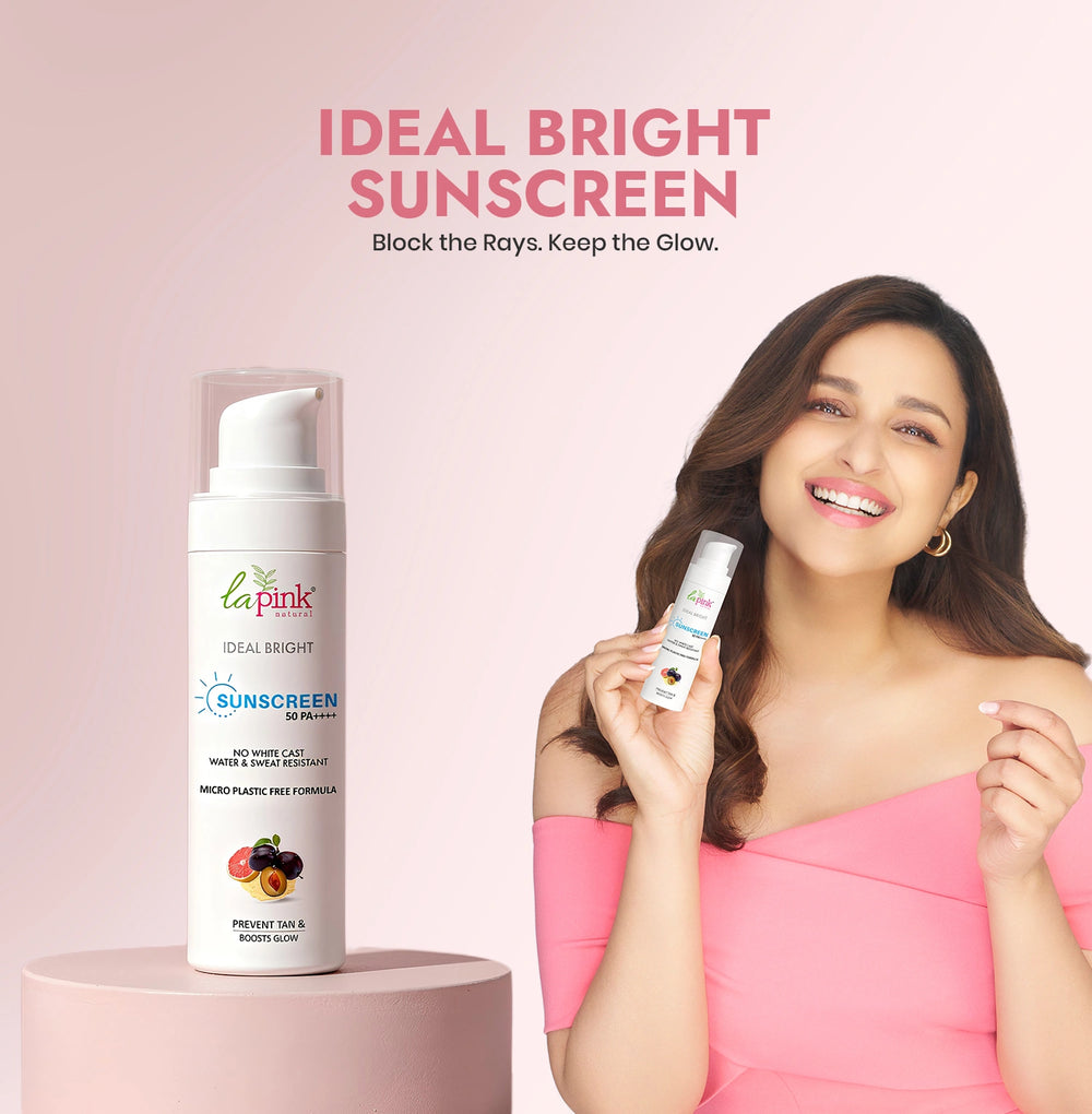 Woman holding a bottle of 'La Pink' Ideal Bright Sunscreen with product packaging on a pink background.