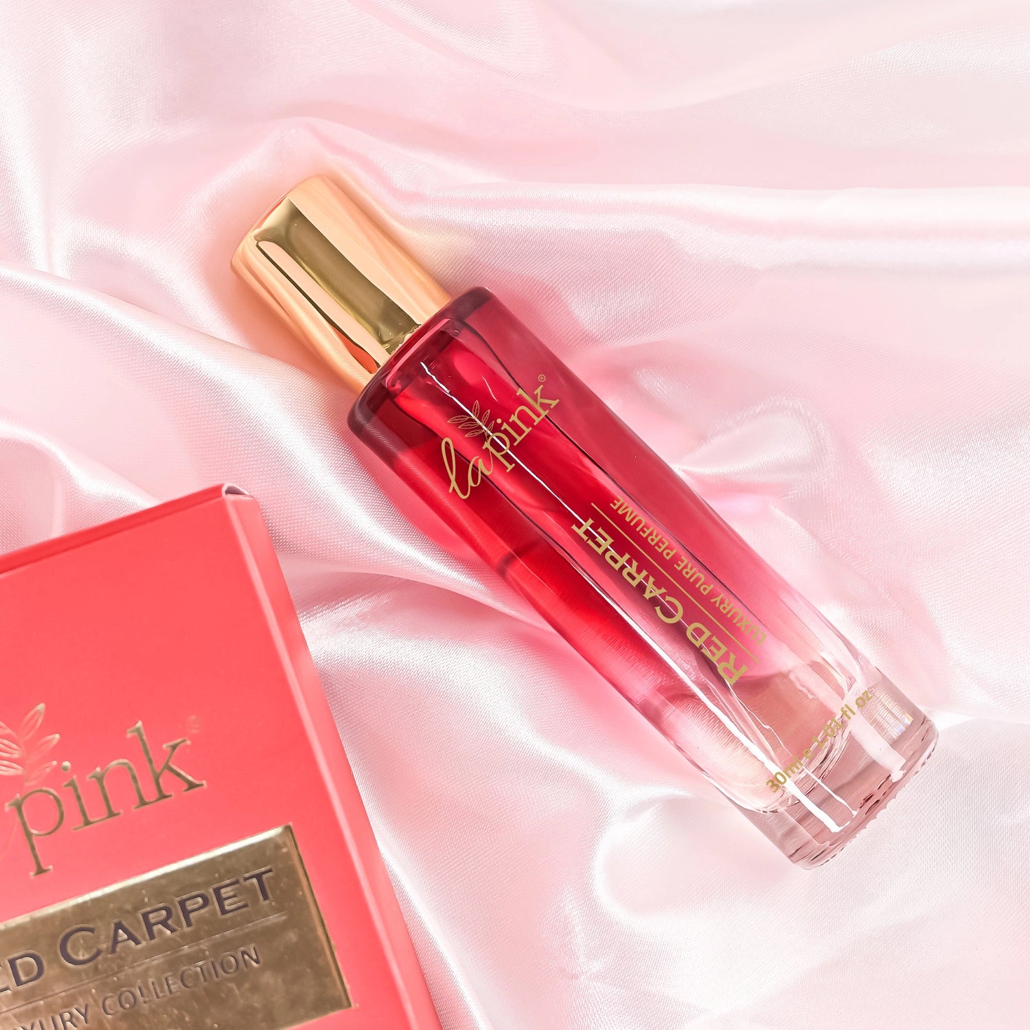 Red lip gloss with gold cap on a pink satin background