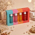 LA PINK body mist set in a colorful box with four different scents: Aqua Pell, Pure Love, Dream Romance, and Wild Secret. The set is styled on a beige surface with decorative dried flowers, pearls, and gift boxes in the background.

