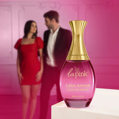 La Pink Love Affair perfume bottle with a blurred couple in the background